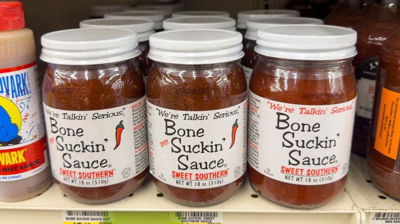 Several jars of Sweet Southern Bone Suckin' Sauce on grocery store shelf.