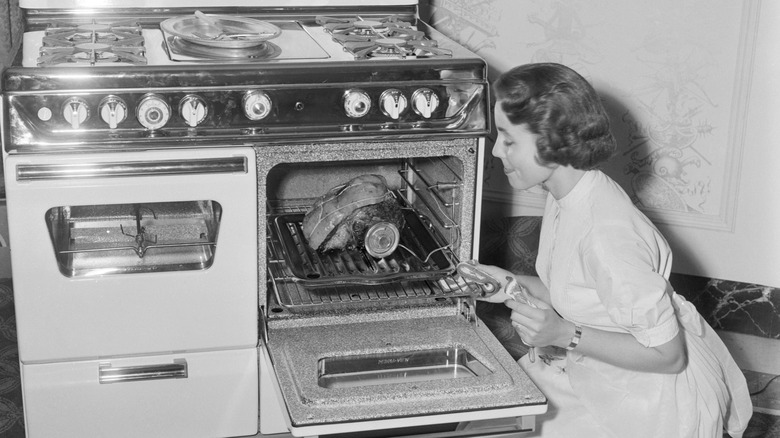 1950s housewife checking meat in the oven with a thermometer