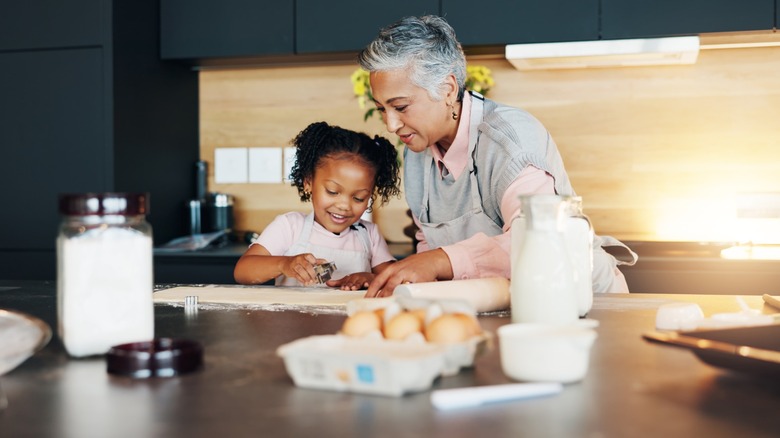 little girl makes cookies with older woman in kitchen