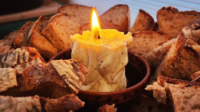 candle made of butter in the center of a platter of sliced bread