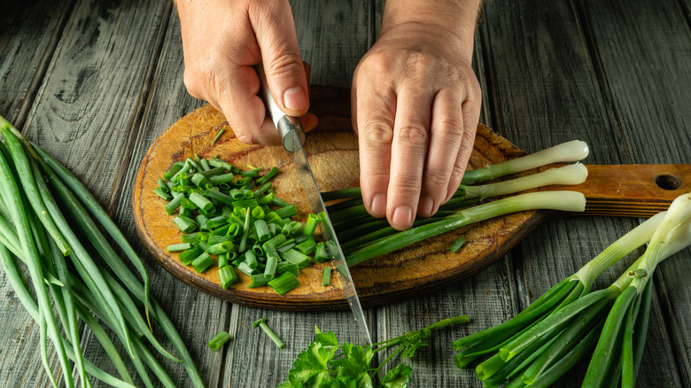Cutting green onions with a knife overhead view.