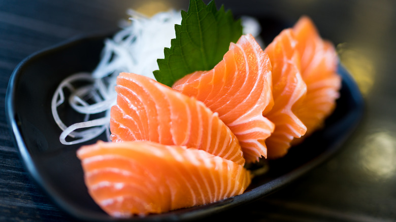 Sliced salmon sashimi in a black bowl