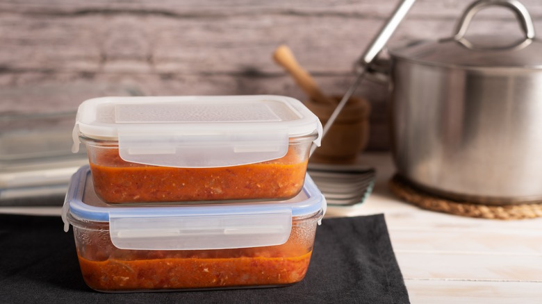 Two glass containers full of soup ready to be frozen.