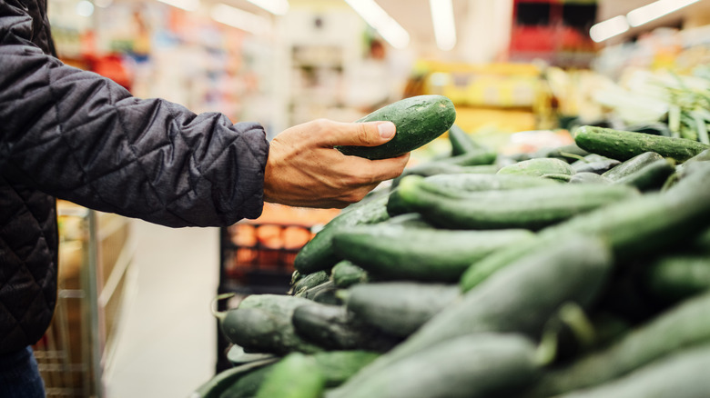 Man holding a cucumber in a grocery store