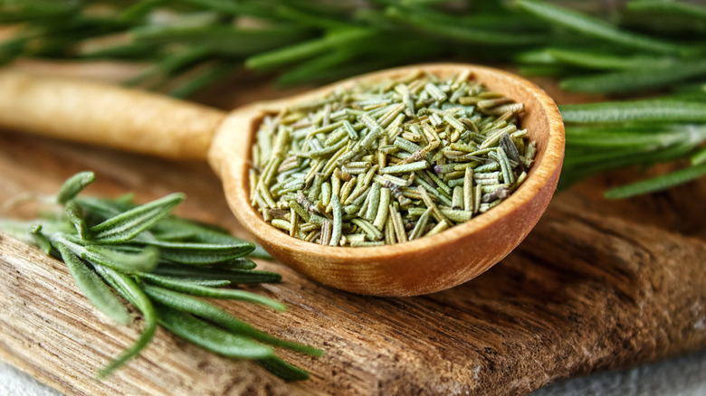 Dry and fresh rosemary on a wooden cutting board.