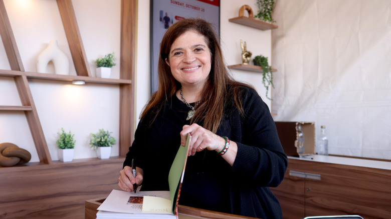 Alex Guarnaschelli smiles while signing a book.