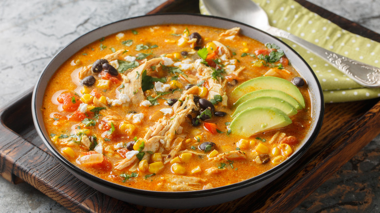 Closeup of chicken enchilada and black bean soup with avocado