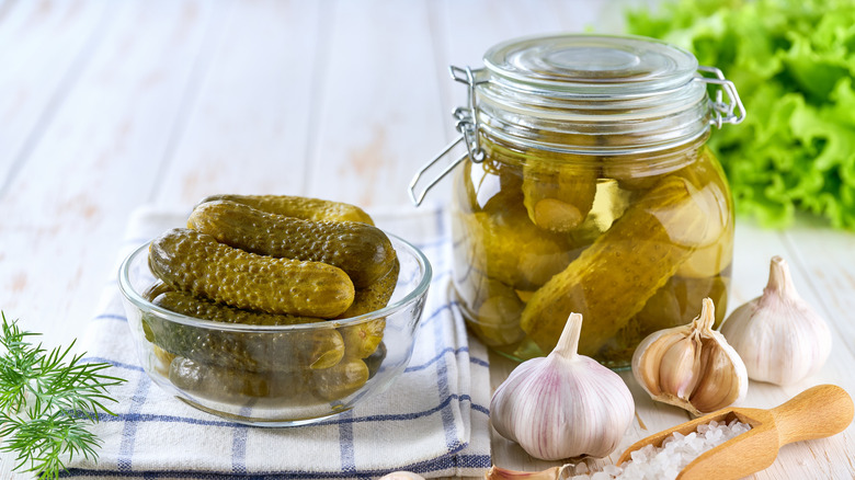Pickles in small ramekin and glass jar with garlic and salt.