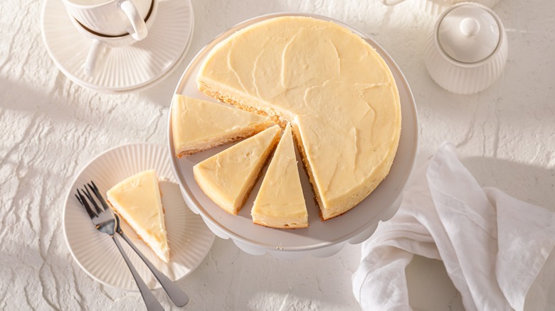 cut cheesecake on white surface with place settings