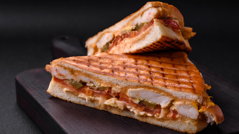Grilled chicken sandwich with tomatoes, pickles, and other fillings.