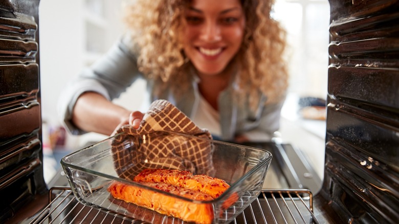 woman cooks salmon in oven