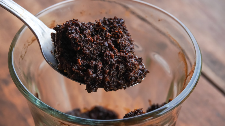 Scooping coffee grounds from cup with spoon