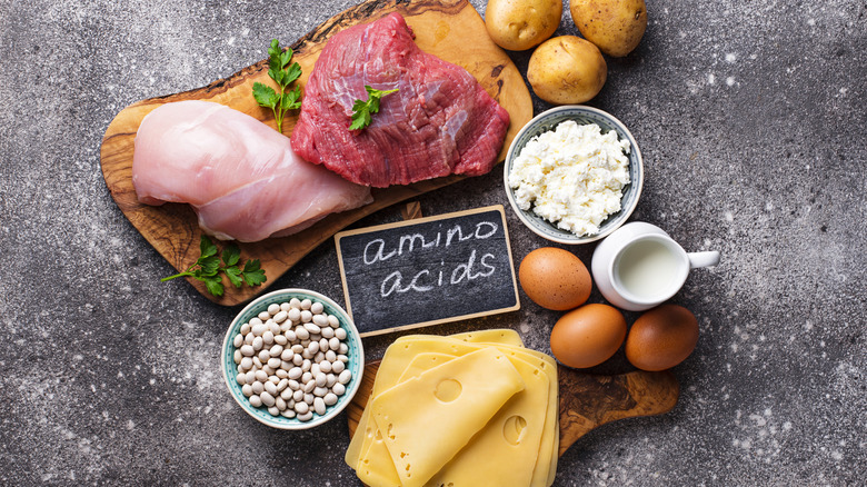A selection of foods surrounding a board with amino acids written on it