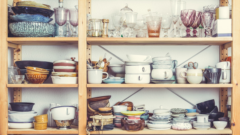 Messy kitchen shelves cluttered with dishes and glasses