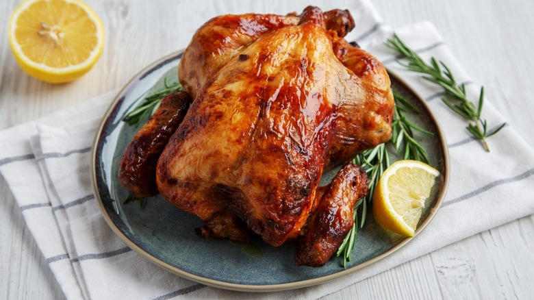 gorgeous golden whole chicken on platter with rosemary and lemon