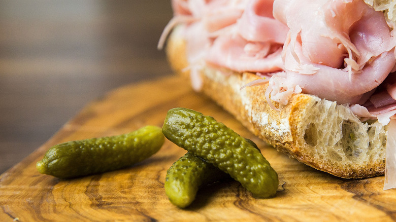 Cornichons on wood board with turkey sandwich.