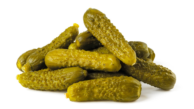 Pile of small, green cornichon pickles.