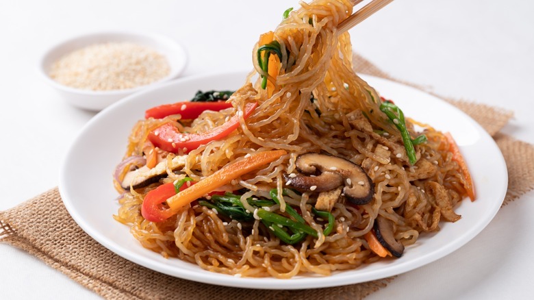 chopsticks lift noodles from a delicious stir fry