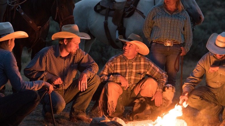 cowboys gather around a campfire
