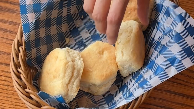 Hand reaching for Cracker Barrel biscuit, overhead view.