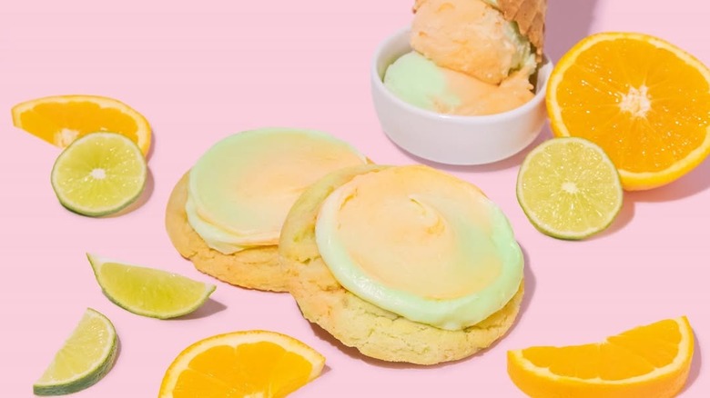 Two Crumbl Sherbet cookies surrounded by citrus fruit