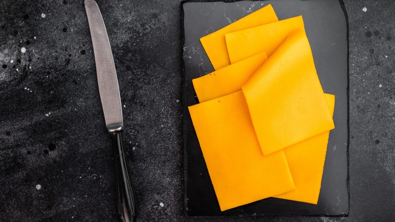 slices of cheese on board with knife