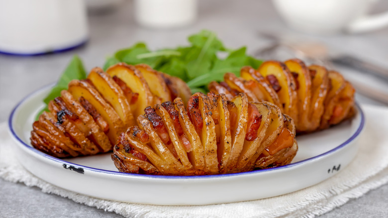 Bacon Hasselback potatoes served on a white plate.