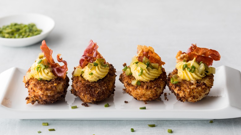 Gourmet deep fried deviled eggs with chives and cooked prosciutto