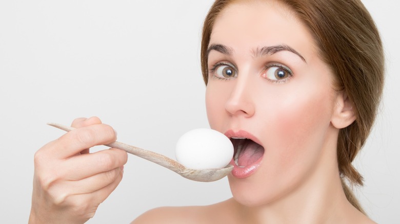 a woman holds an egg on a wooden spoon