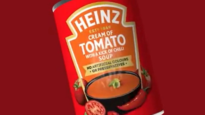 A close-up of a can of Heinz Cream of Tomato Soup with a Kick of Chilli on a red background