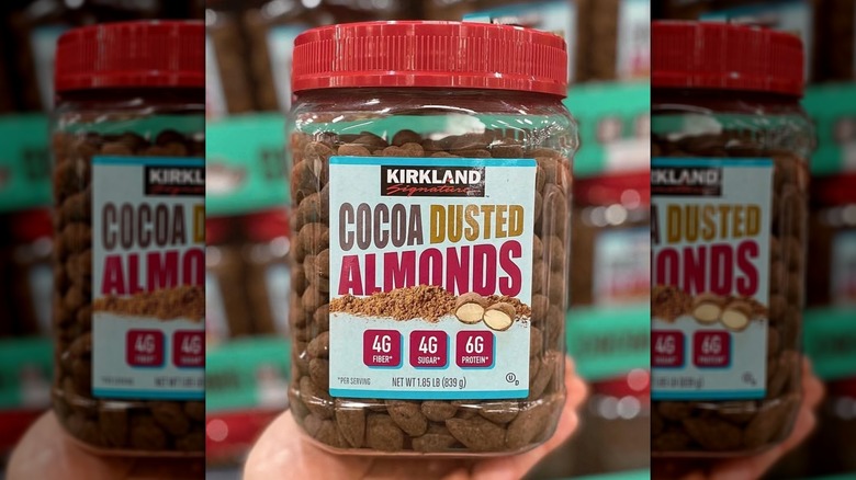 Someone holding a jar of Kirkland Signature Cocoa Dusted Almonds
