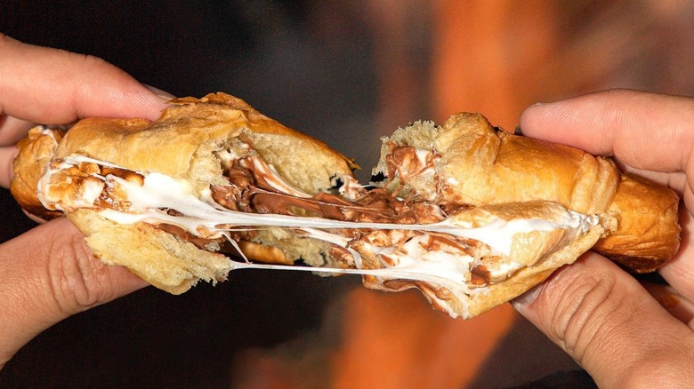 hands pulling apart a croissant filled with melted chocolate and marshmallow 