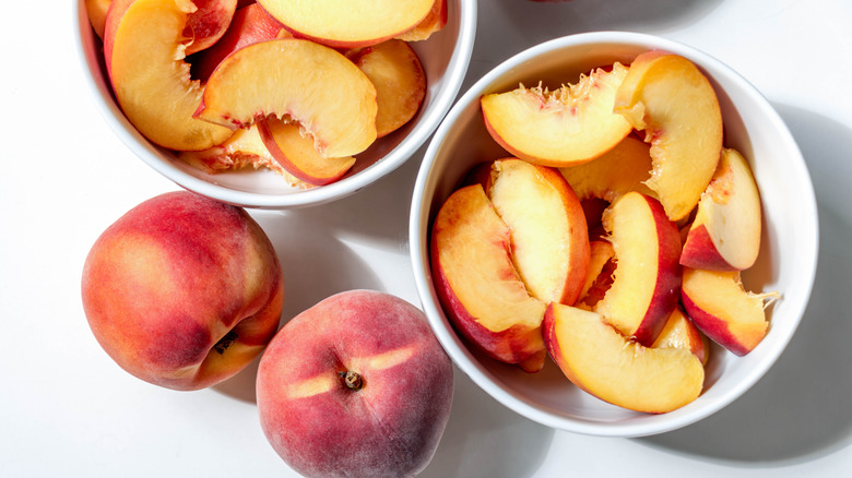 Whole and sliced peaches in bowls.