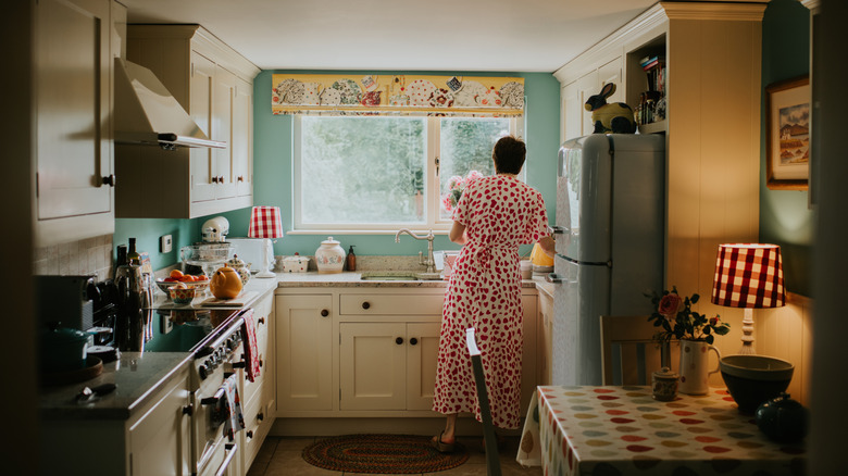 Woman standing at sink in retro-styled kitchen.
