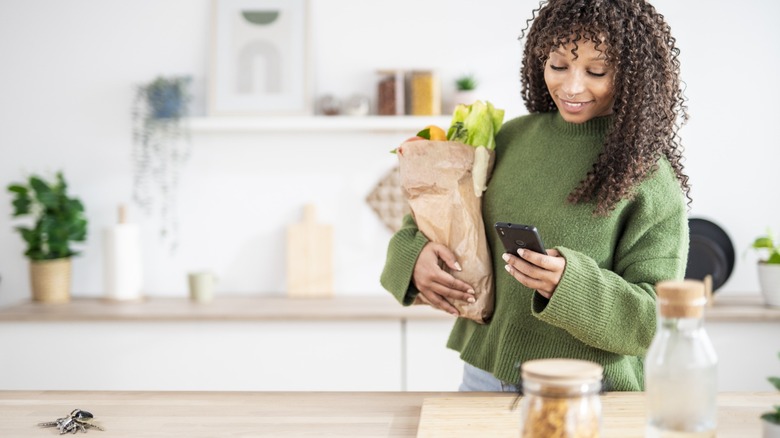 a woman shops for groceries on her phone