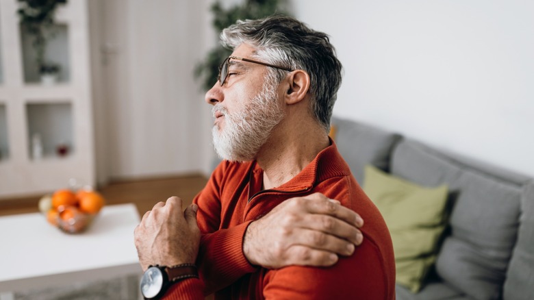 man nurses a sore shoulder