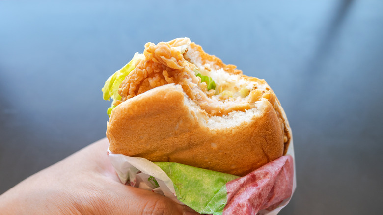 Closeup fried chicken sandwich with bite taken out.