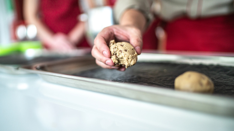 hand placing scoops of cough dough on baking sheet