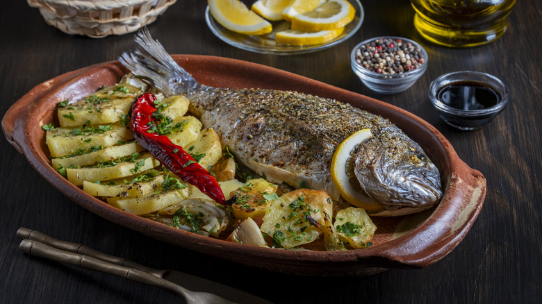 Whole roasted mahi-mahi on plate with potatoes