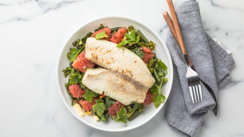 tilapia on a plate with a fruity salad