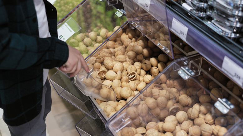 A close-up of someone scooping nuts out of the bulk section at a supermarket