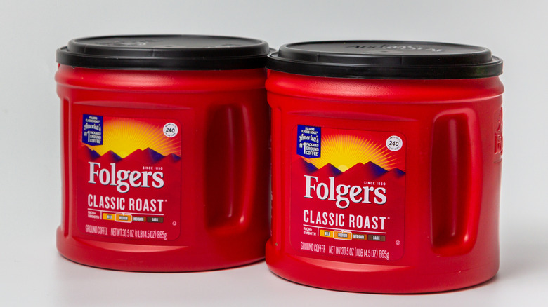 Two plastic containers of Folger's coffee on neutral background.