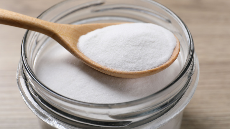Close-up of a spoonful of baking soda in a glass jar