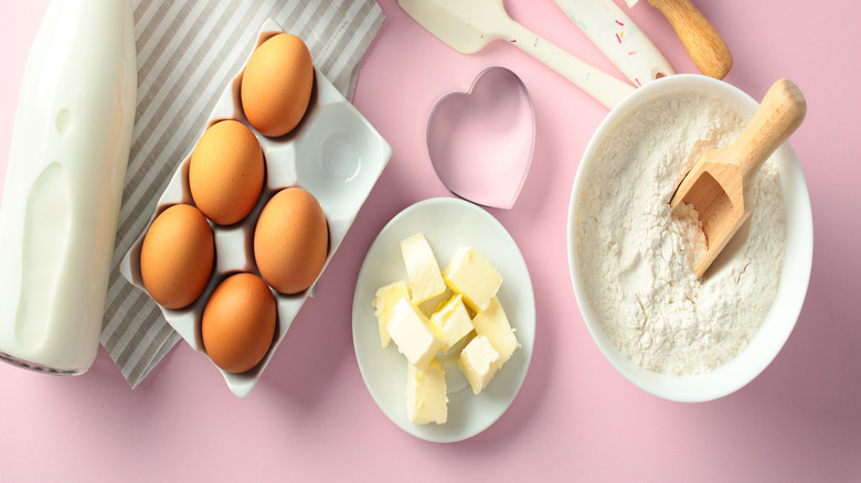 Baking ingredients and tools on a pink background
