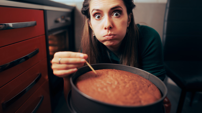 Woman trying to check if her cake is done using a toothpick