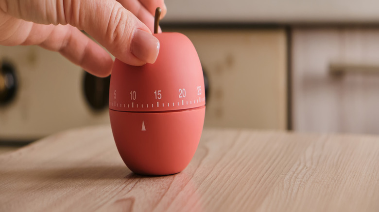 hand turning an apple-shaped kitchen timer
