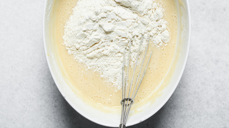 Overhead view of flour being mixed into cake batter