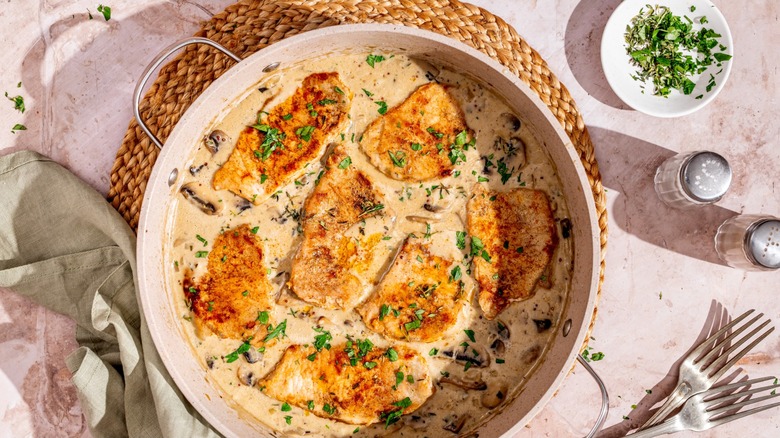 pork chops in a pan with cream sauce and mushrooms