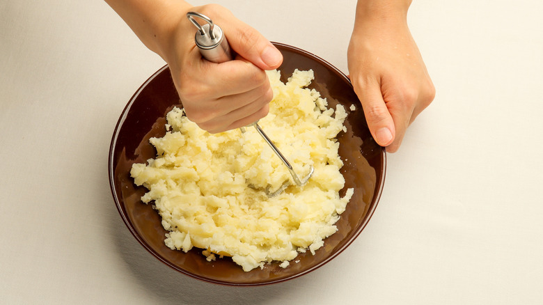 Potatoes being mashed in dish