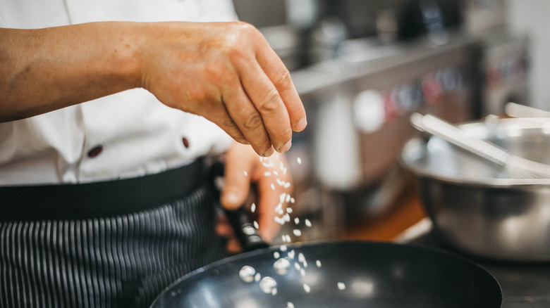 Cook flavoring a dish with spices